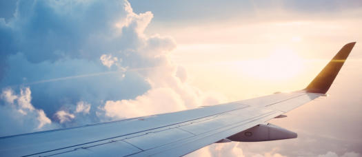 Anwalt für Reiserecht - Tragfläche eines Passagierflugzeugs über den Wolken mit Verspätung